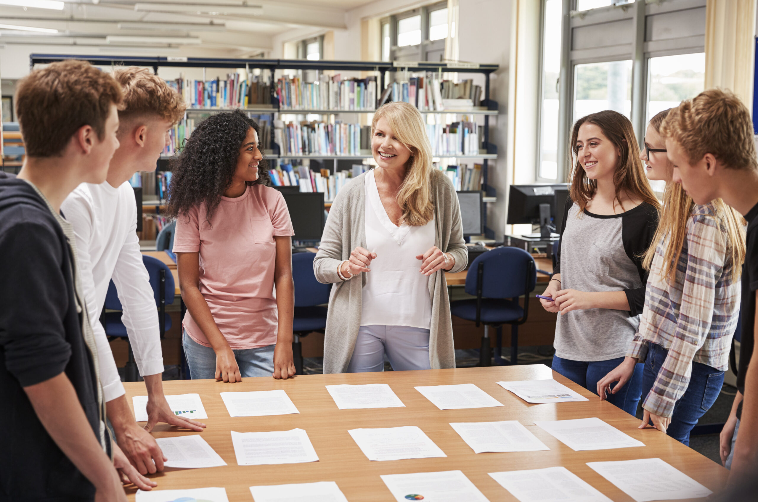 Female Teacher Working With College Students In Library