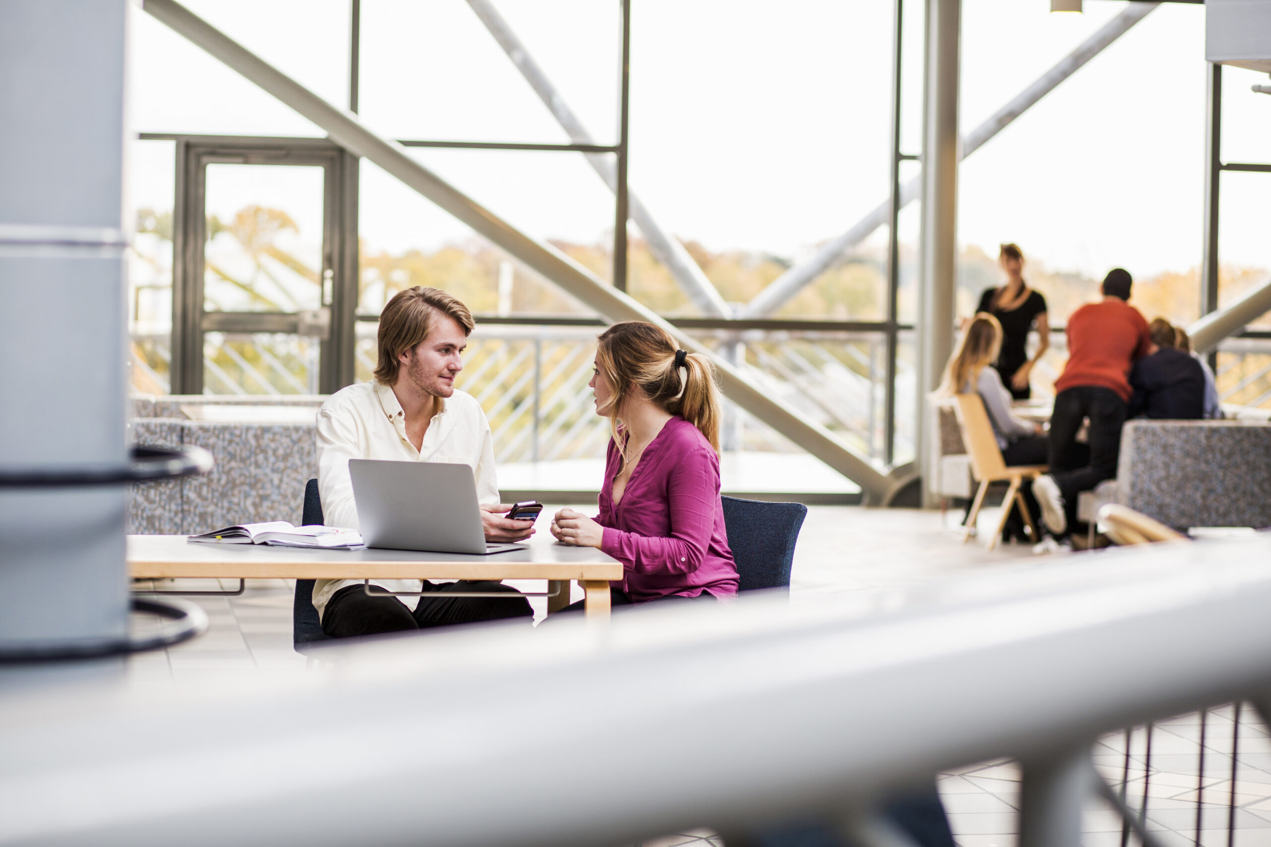 Young friends communicating at table in university